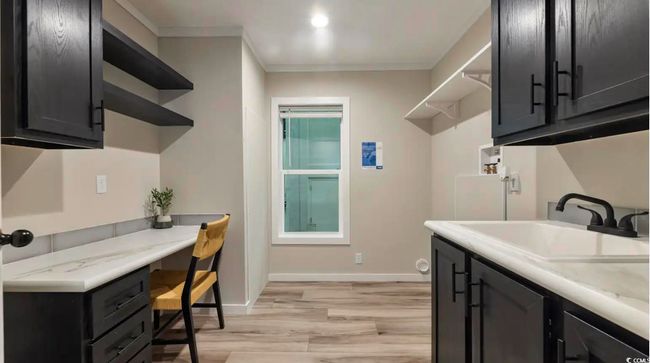 Laundry room featuring a sink, crown molding, light wood-style flooring, baseboards, and an office area | Image 35