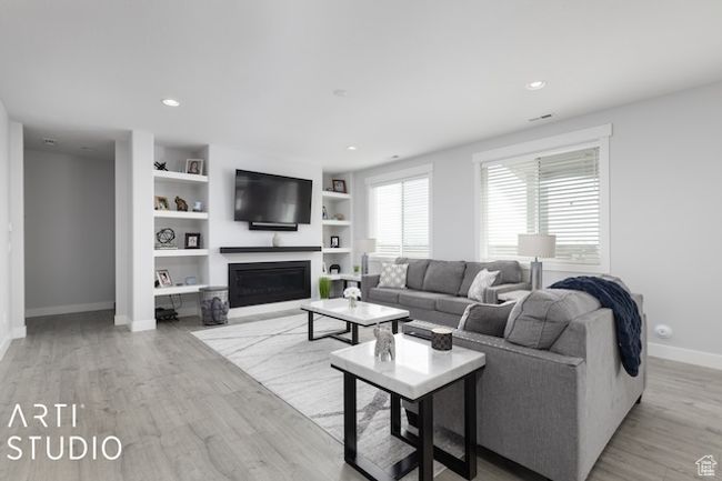 Living room featuring built in shelves, a glass covered fireplace, recessed lighting, light wood-style floors, and baseboards | Image 16