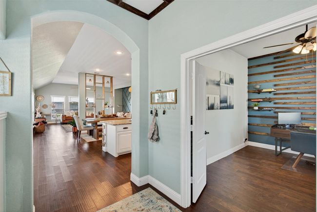Corridor with dark wood finished floors, vaulted ceiling, arched walkways, a desk, and recessed lighting | Image 9