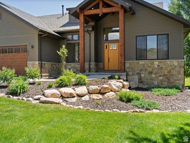 View of front of home with stone siding, roof with shingles, an attached garage, and a front yard | Image 54