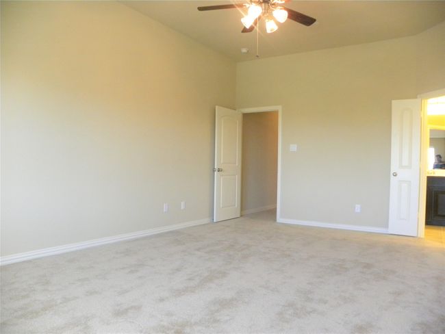 Unfurnished bedroom with light colored carpet, ensuite bathroom, and ceiling fan | Image 23