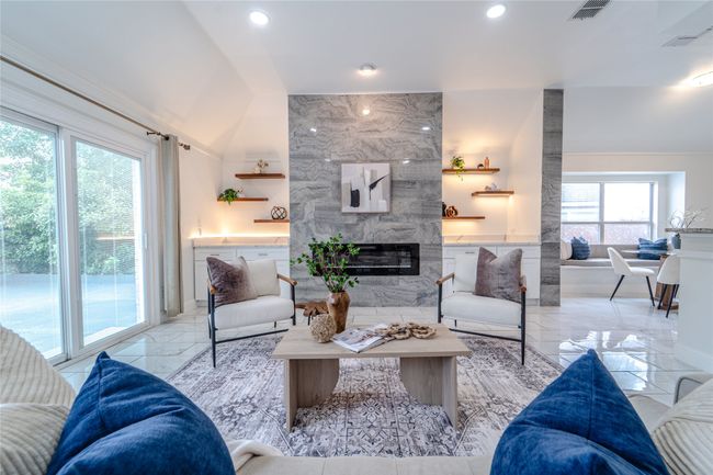 Living area with a fireplace, light marble finish flooring, recessed lighting, and lofted ceiling | Image 12
