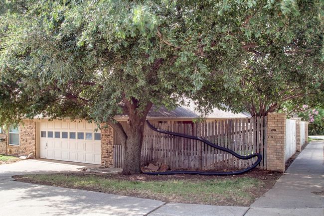 Obstructed view of property featuring an attached garage, brick siding, and driveway | Image 25