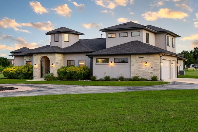 View of front of property with stone siding, concrete driveway, a front yard, stucco siding, and an attached garage | Image 6