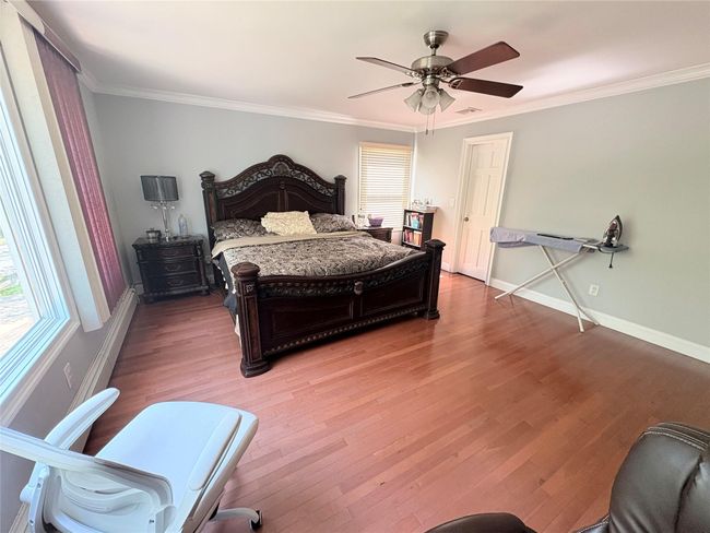 Bedroom with crown molding, light wood-type flooring, baseboards, and a ceiling fan | Image 16