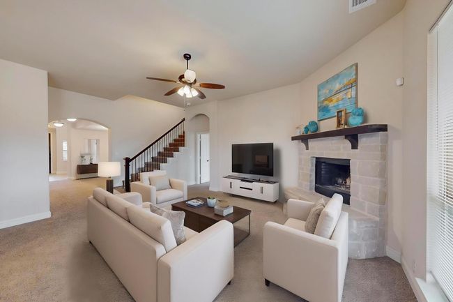 Living room featuring arched walkways, carpet, a fireplace, a ceiling fan, and baseboards | Image 7