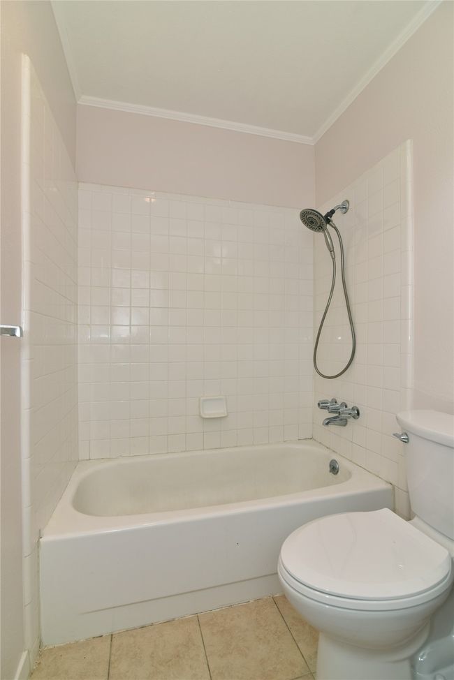 Bathroom with ornamental molding, toilet, tile patterned floors, and washtub / shower combination | Image 23