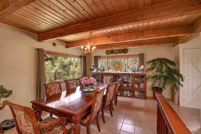 Dining room featuring a chandelier, a wood ceiling with exposed beams, and light tile patterned flooring | Image 15