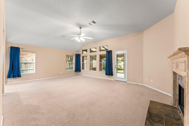 This spacious family room offers incredible space to relax or entertain, with vaulted ceilings and a gas fireplace adding warmth and charm. A wall of windows frames views of the backyard, while direct access to the sunroom extends the living space with natural light and flexibility. | Image 16