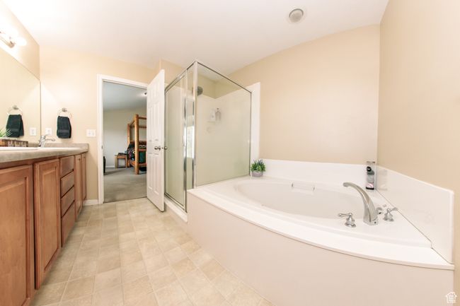 A full bath with a separate shower and relaxing soaker tub, double sink vanity, and tile flooring. | Image 20