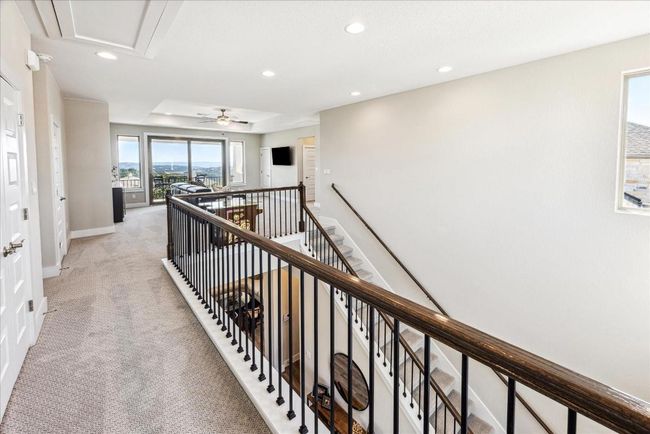 A hallway-style catwalk leads to two upstairs bedrooms, where elevated, patterned carpet adds a stylish touch to the second floor. | Image 27