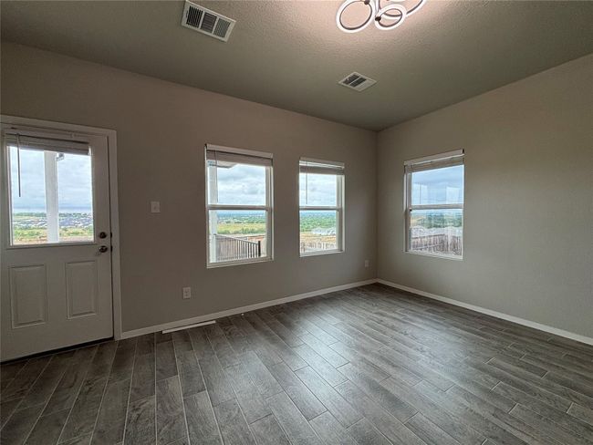 Unfurnished room featuring dark wood finished floors, baseboards, a textured ceiling, and a chandelier | Image 17