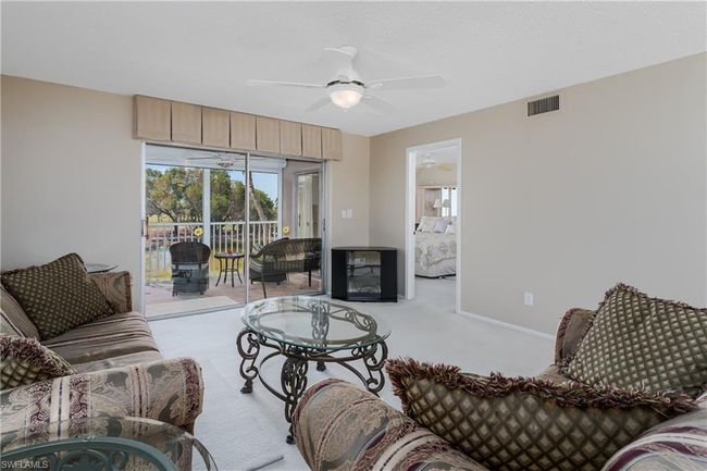 Carpeted living room featuring visible vents, baseboards, and ceiling fan | Image 8