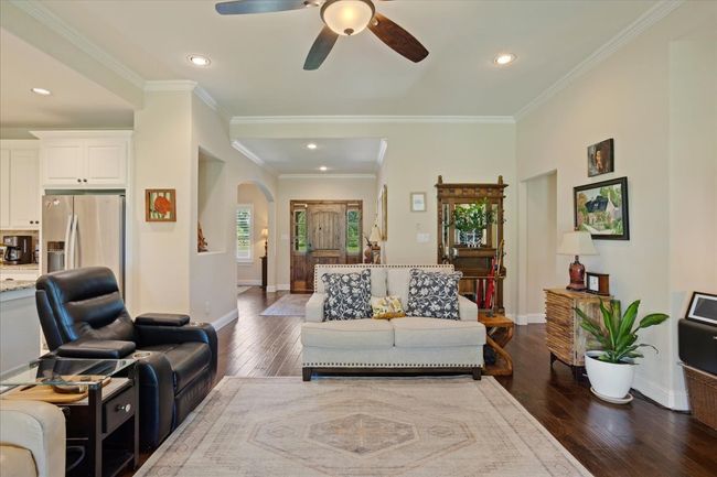 Living area featuring arched walkways, a ceiling fan, dark wood-style floors, baseboards, and ornamental molding | Image 6