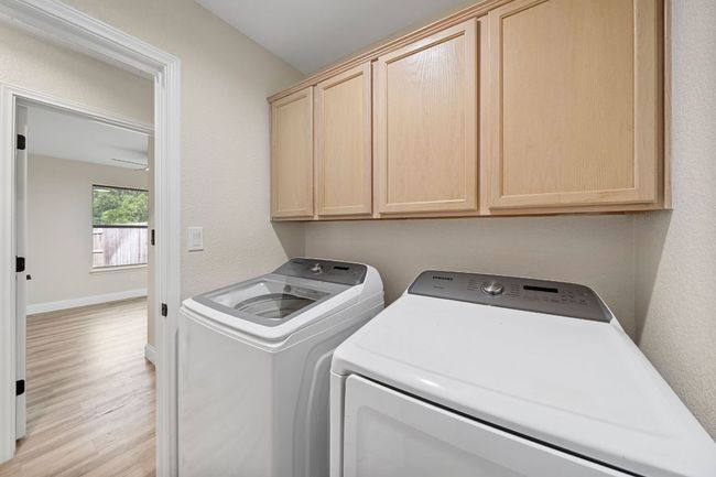 Laundry area featuring washing machine and dryer, cabinet space, and light wood-type flooring | Image 17