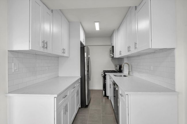 Kitchen with appliances with stainless steel finishes, light countertops, backsplash, and white cabinetry | Image 4