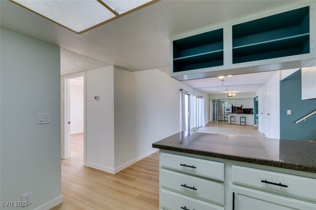 Kitchen featuring light wood-style flooring, dark stone counters, open shelves, and white cabinets | Image 27