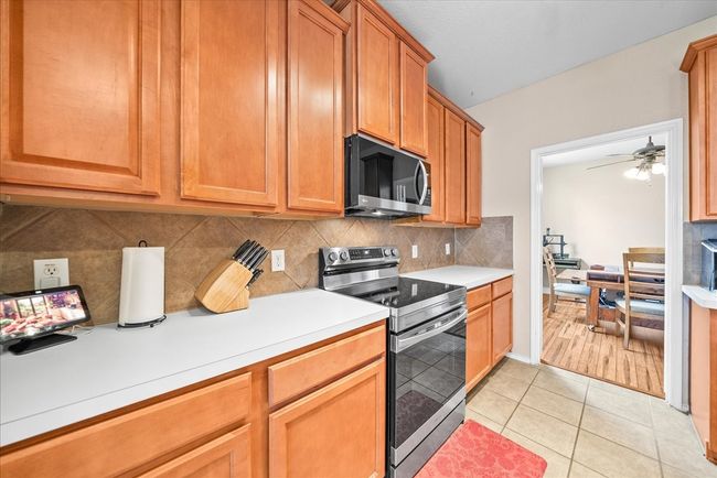 Kitchen featuring stainless steel appliances, light countertops, backsplash, and ceiling fan | Image 26