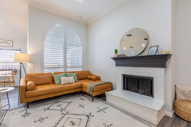 Living area with wood finished floors, ornamental molding, a fireplace, and baseboards | Image 10