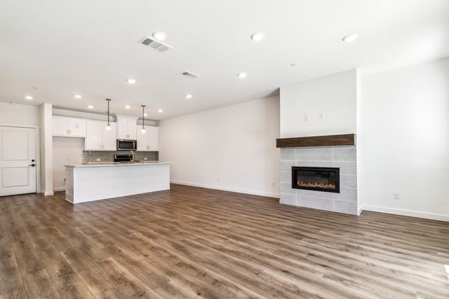 Unfurnished living room featuring wood finished floors, baseboards, a tile fireplace, and recessed lighting | Image 7