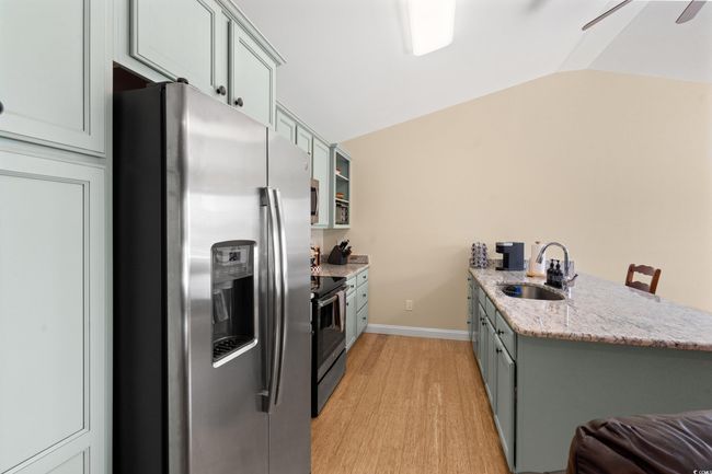 Kitchen with stainless steel appliances, a sink, a peninsula, light wood finished floors, and lofted ceiling | Image 6