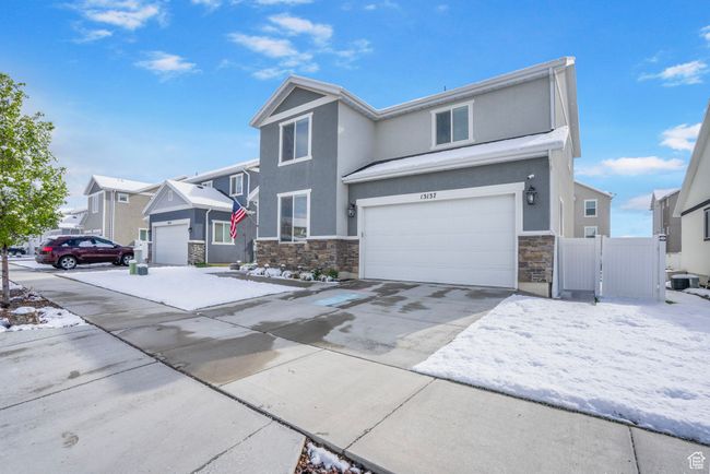 View of front of house with concrete driveway, stone siding, an attached garage, fence, and stucco siding | Image 33