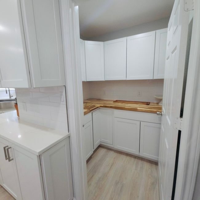 Kitchen featuring tasteful backsplash, wooden counters, and white cabinets | Image 12