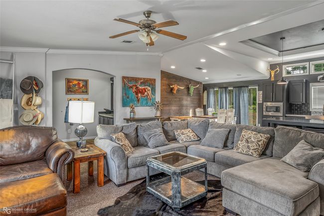 Living area featuring recessed lighting, arched walkways, vaulted ceiling, ornamental molding, and a ceiling fan | Image 15