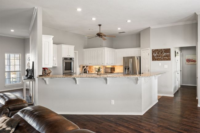 Kitchen featuring stainless steel appliances, a peninsula, a ceiling fan, and crown molding | Image 9