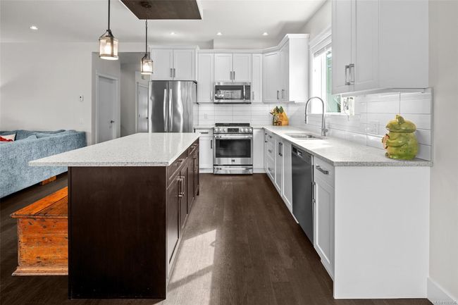 Kitchen featuring stainless steel appliances, white cabinetry, dark wood-style floors, decorative backsplash, and recessed lighting | Image 18