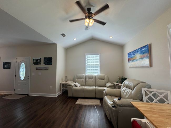 Living room with a ceiling fan, dark wood-style floors, lofted ceiling, plenty of natural light, and baseboards | Image 5