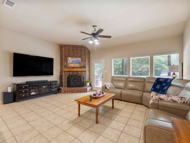 Living room with light tile patterned flooring, ceiling fan, and a fireplace | Image 6