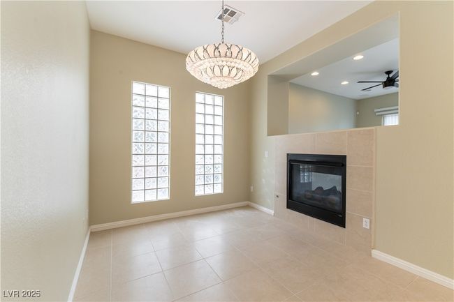 Unfurnished living room with a fireplace, ceiling fan with notable chandelier, baseboards, visible vents, and recessed lighting | Image 4