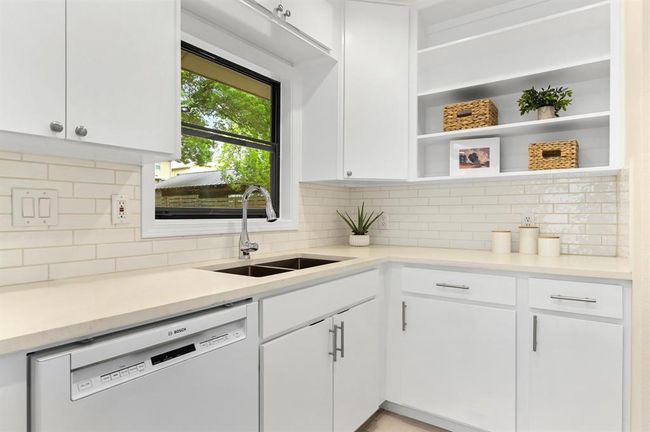 Kitchen featuring white dishwasher, white cabinets, open shelves, light countertops, and backsplash | Image 10