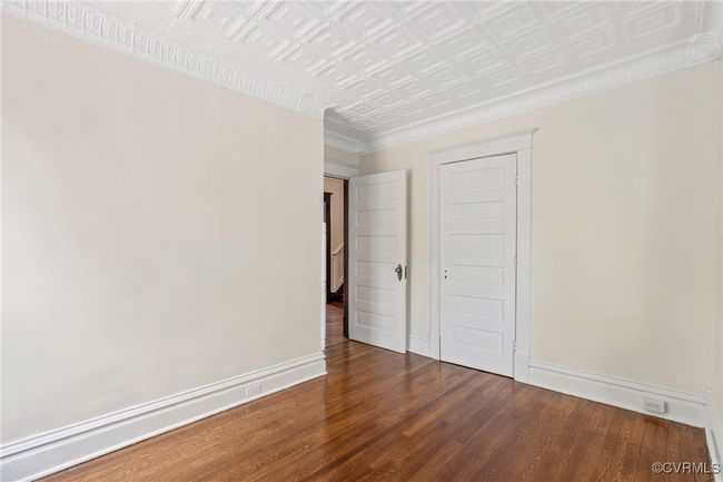 Bedroom featuring wood finished floors, an ornate ceiling, and baseboards | Image 30
