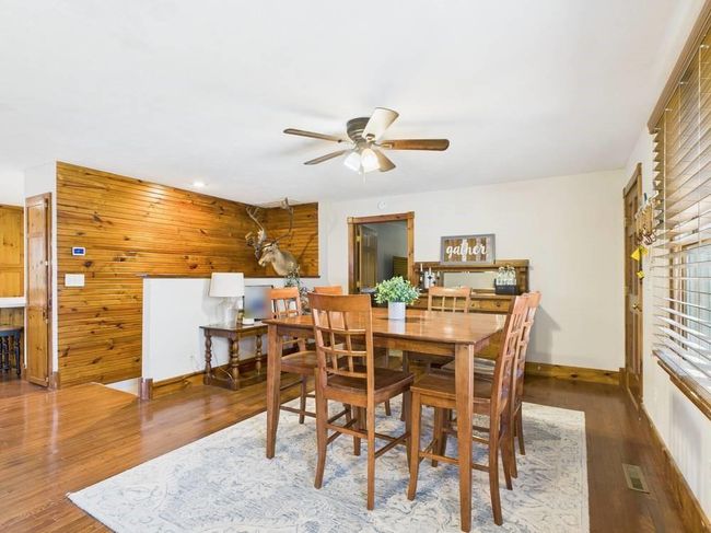 Dining area with wooden walls, baseboards, a ceiling fan, and wood finished floors | Image 19