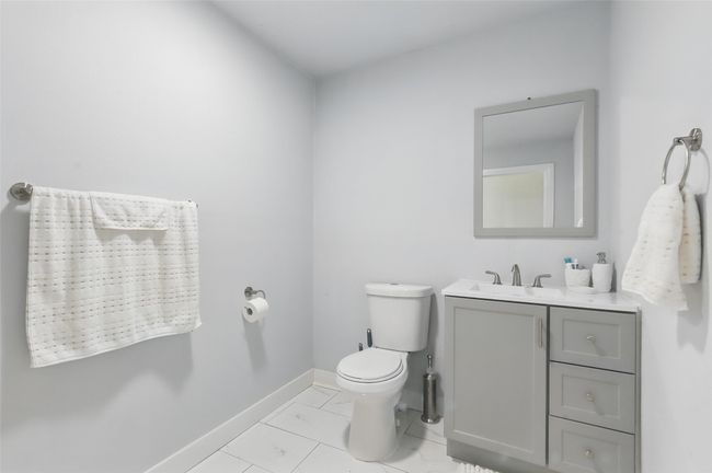 Half bath with toilet, baseboards, vanity, and marble look tile flooring | Image 17