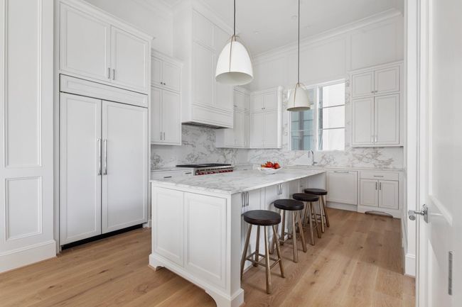 A chef’s dream, this kitchen features a 10' marble island, floor-to-ceiling cabinetry, and designer lighting. | Image 13