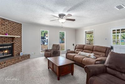 Living room featuring a healthy amount of sunlight, a fireplace, and a textured ceiling | Image 3