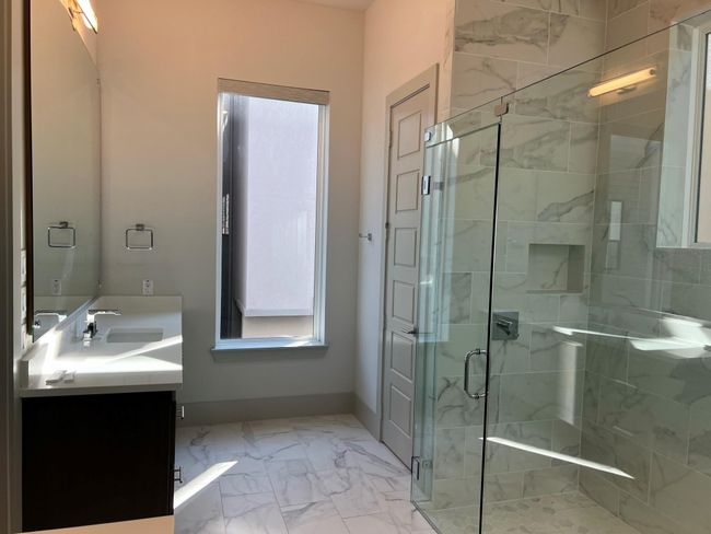 Full bath with marble look tiles, vanity, a stall shower, and baseboards | Image 24