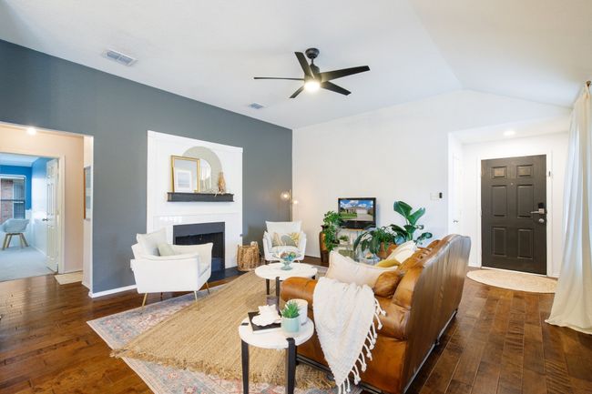 Living room with a fireplace, ceiling fan, dark wood finished floors, and lofted ceiling | Image 4