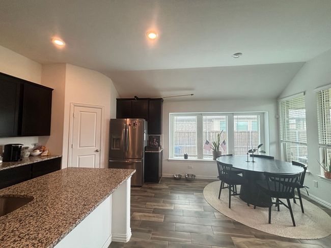 Kitchen featuring stainless steel fridge, vaulted ceiling, light stone counters, plenty of natural light, and dark wood-style floors | Image 8