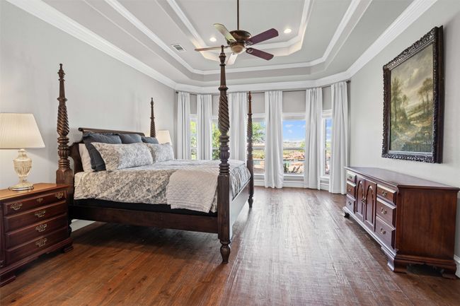 Bedroom with visible vents, ornamental molding, a ceiling fan, dark wood-style floors, and a tray ceiling | Image 19
