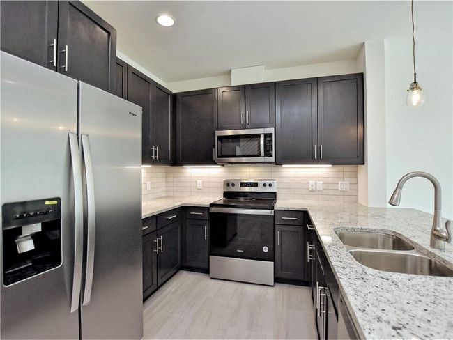 Kitchen with stainless steel appliances, light stone counters, decorative backsplash, decorative light fixtures, and recessed lighting | Image 9