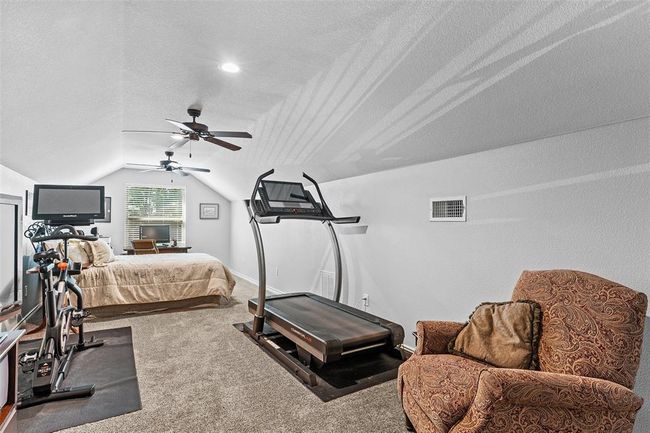 Exercise room with lofted ceiling, ceiling fan, carpet, and a textured ceiling | Image 18