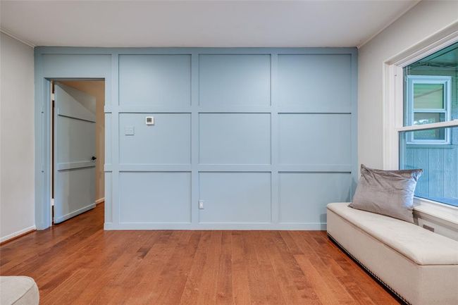Living Room features a stylish recently installed, light blue accent wall with paneling, rich hardwood floors, offering a bright and inviting space. | Image 10
