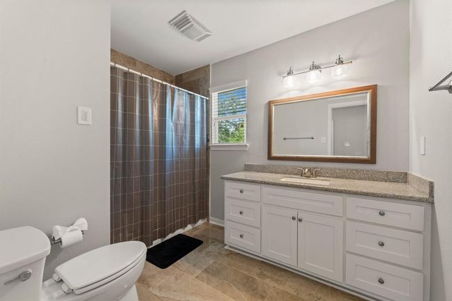 This bathroom features a modern design with a spacious vanity and ample cabinet space. It includes a walk-in shower with a large mirror and overhead lighting. | Image 33
