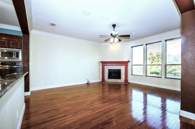 Unfurnished living room featuring a ceiling fan, dark wood-type flooring, ornamental molding, a high end fireplace, and baseboards | Image 6