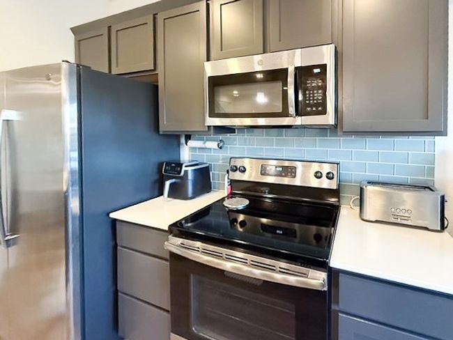 Kitchen featuring appliances with stainless steel finishes, brown cabinetry, and tasteful backsplash | Image 7