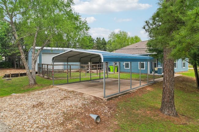 View of vehicle parking with driveway, a detached carport, and fence | Image 4